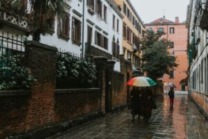 Menschen mit bunten Regenschirmen in einer regennassen Gasse