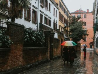 Menschen mit bunten Regenschirmen in einer regennassen Gasse
