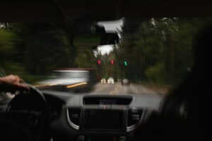 Fahrerblick bei Regen mit verschwommenen Lichtern und Ampelsignalen