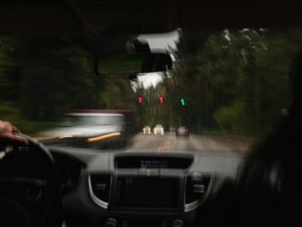 Fahrerblick bei Regen mit verschwommenen Lichtern und Ampelsignalen